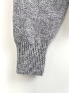 Close-up of gray knitted hoodie cuff showing high-quality ribbed texture and warm fiber detail