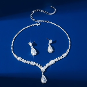 Elegant silver necklace and earring set featuring teardrop crystals on deep blue background
