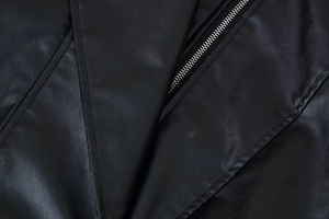 Close-up of grain texture and silver metal zipper on women's black leather jacket