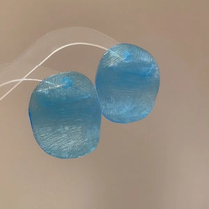 Detailed view of translucent sky blue acrylic resin charms with unique brushed texture