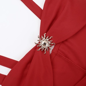 Detailed close-up of a red knitted dress featuring a sun-shaped metallic gold ornament