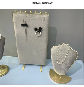 Detail display of grey velvet jewelry stands with pearl earrings and heart necklace
