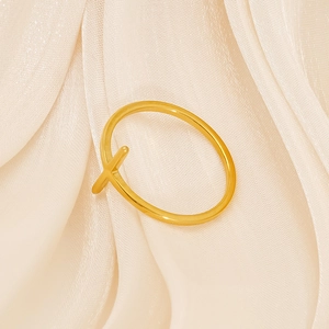 Macro shot of polished gold-finished cross X-shaped ring on elegant beige satin fabric