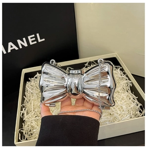 Close-up of silver bow-shaped metal evening clutch bag with fine chain and luxury box