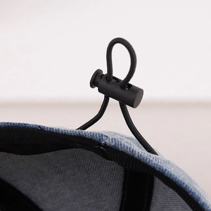 Macro detail of adjustable drawstring toggle and denim fabric texture on the sun hat