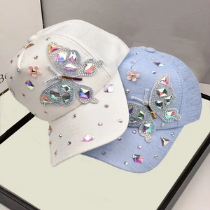 Close-up of sparkling crystal butterfly rhinestones and pink floral details on baseball caps