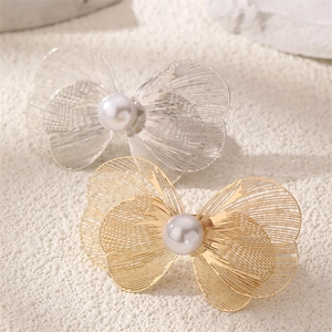 Detailed macro view of butterfly filigree wings with pearl center in gold and silver