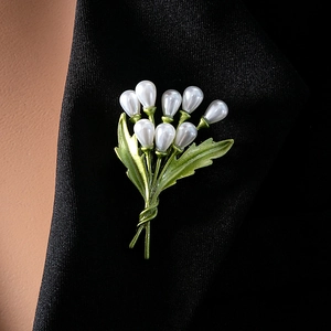 Detailed close-up of lily of the valley brooch with pearls on black suit lapel