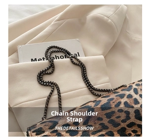 Detail of trendy leopard print handbag showing metal chain strap and premium faux leather