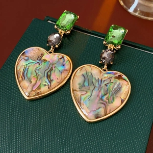 Detailed close-up of vintage heart earrings with green crystals on a jewelry box