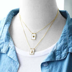 Close-up of double-layer gold necklaces with heart and Virgin Mary rectangle pendants