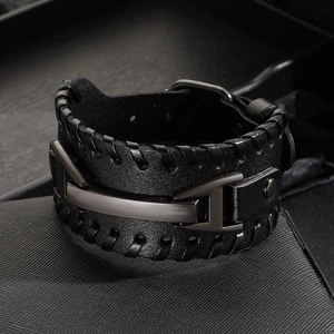 Vintage black leather woven bracelet with large dark metal buckle on textured background