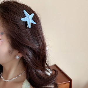 Close-up of light blue starfish hair clip with pearl accents worn on the side hair