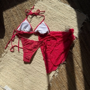 Detailed close-up of red floral lace bikini set with matching mesh wrap skirt