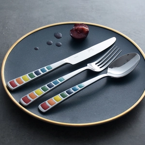 Rainbow enamel stainless steel cutlery set with knife, fork, and spoon on a grey plate