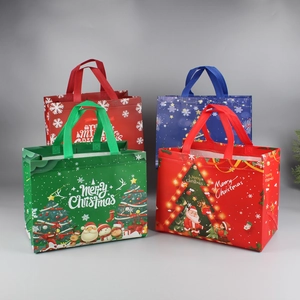 Close-up of four assorted Christmas non-woven gift bags with festive Santa and tree patterns