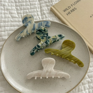French gradient marble hair claws in blue, green and beige colors displayed on a plate