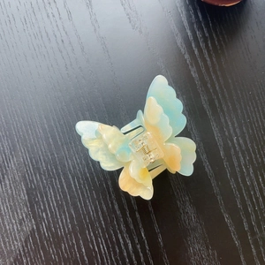 Macro detail of 3D butterfly hair claw with blue yellow gradient and pearl finish