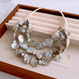 Detail of bohemian triple-layered necklace with iridescent natural shell fragments