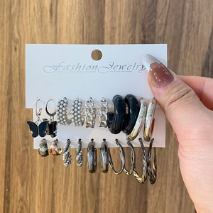 Close-up of a diverse earring set featuring black butterflies, pearls, and silver chains