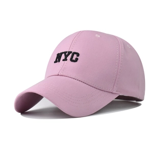 Close-up of pink cotton baseball cap featuring black NYC letter embroidery and curved brim