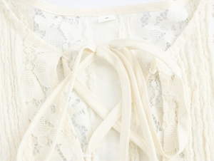 Macro view of white lace collar with tie-up design and intricate fabric texture details