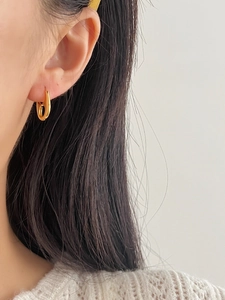 Close-up of a model wearing a gold polished irregular oval hoop earring in 925 silver