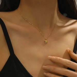 Close-up of minimalist gold heart pendant necklace worn by a model with elegant black dress