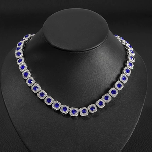 Close-up of square blue sapphire necklace with crystal accents on a black display stand