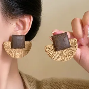 Ethnic style earrings featuring dark wood blocks and beige raffia fan-shaped woven tassels