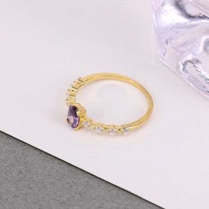 Detailed view of a gold ring featuring a large oval purple stone and clear side crystals