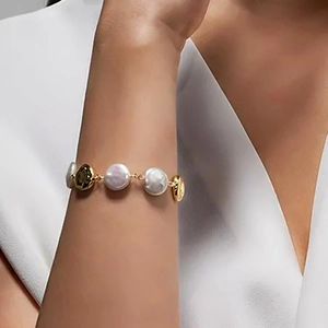 Vintage stainless steel pearl bracelet with textured gold discs on woman's wrist