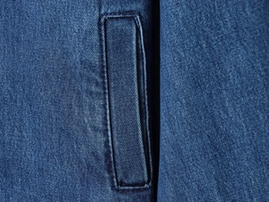 Primo piano di una tasca in denim cucita su una giacca con colletto in velluto blu scuro
