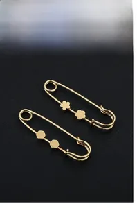Close-up of golden safety pins with flower and geometric patterns for clothing adjustment