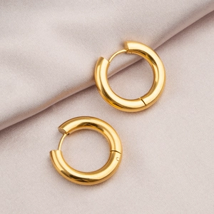 Minimalist high-polished gold hoop earrings in titanium steel on pink silk backdrop