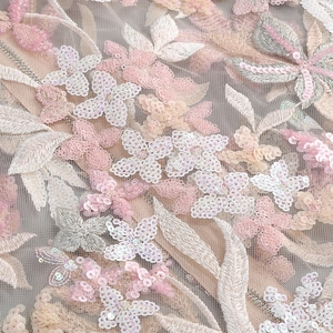 Macro shot of detailed 3D floral embroidery with sequins on luxury mesh dress fabric