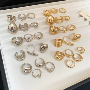 Detailed view of irregular polished bean rings in gold and silver on a jewelry display tray
