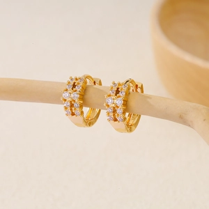 Close-up of gold plated huggie earrings featuring double row pavé white cubic zirconia