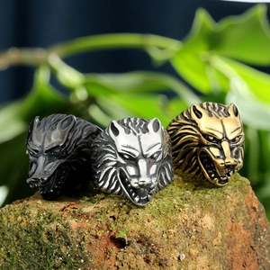 Vintage titanium steel wolf head rings in three metallic finishes on a brick surface