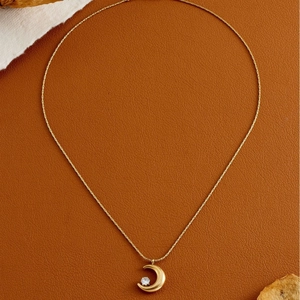 Elegant gold crescent moon necklace featuring a sparkling round zircon on brown leather