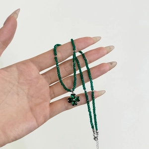Detailed close-up of green clover pendant necklace with luxury crystal zircon beads