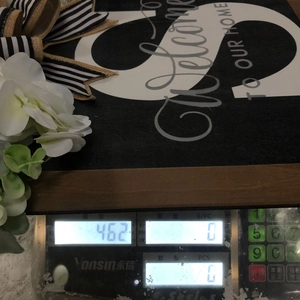 Detail shot of the wooden welcome door sign on a scale showing a weight of 462 grams