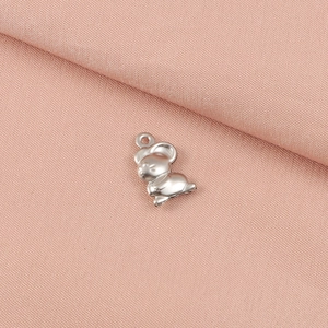 Polished stainless steel mouse charm pendant on soft pink fabric background for DIY jewelry