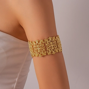 Détail d'un bracelet de bras doré évidé avec des motifs floraux et géométriques