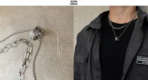 Macro detail of silver layered chain necklace and circular pendant on industrial stone