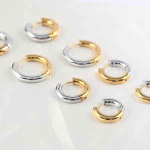 Polished gold and silver stainless steel hoop earrings in multiple sizes on white silk
