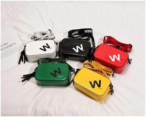 Detail of colorful patent leather crossbody bags with wide letter straps and tassels