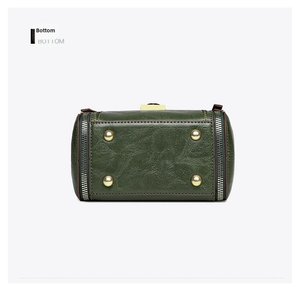 Detail of green bucket bag bottom featuring four gold metal protective feet and zipper base
