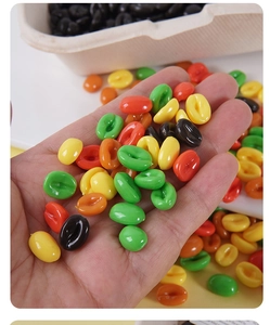 Macro detail of colorful resin coffee bean charms for DIY crafts held in hand