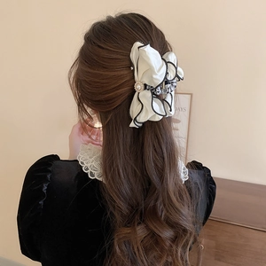 Back view of a model wearing an elegant cream fabric bow hair claw clip with pearl detail